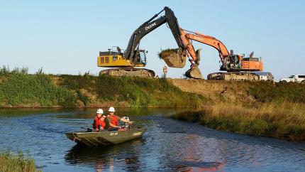 Excavators breach a dike as part of Fir Island restoration project