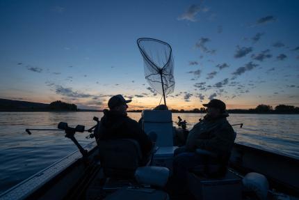 Two fishermen on a boat at sunrise