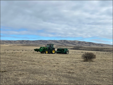 A grass seeder spreading grass into a field