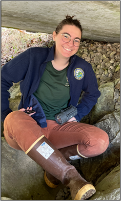 Technician Liepold sitting on a rock in a cave.