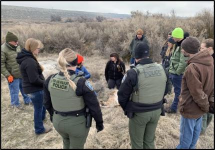 A circle of people in a field conducting training.