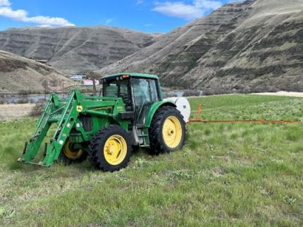 A tractor boom spraying in a field.