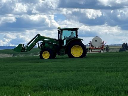 A tractor spraying winter wheat at Smoothing Iron Ridge.