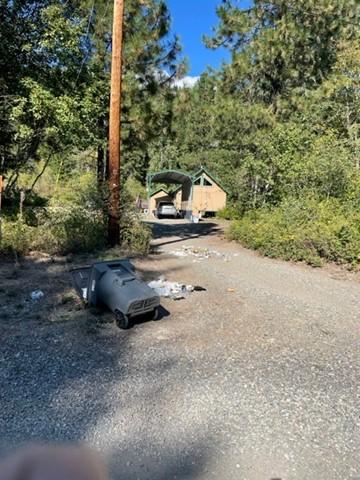 A trashcan knocked over with trash on the road