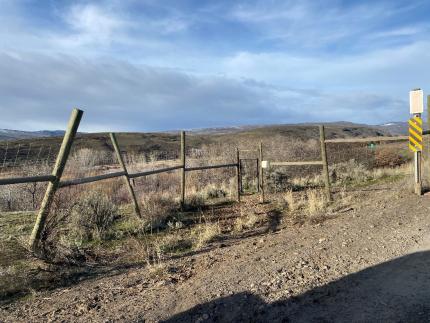 Damaged elk fence with broken posts and large hole in fence.