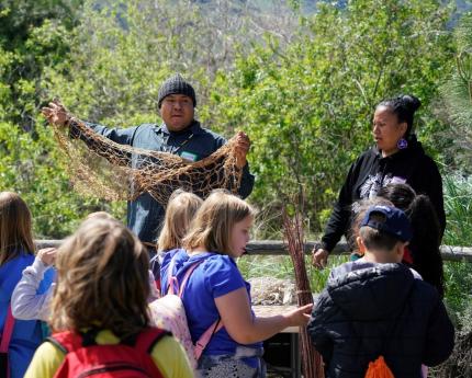 Members of the Confederated Tribes of the Colville Reservation talking with students about traditional practices. 